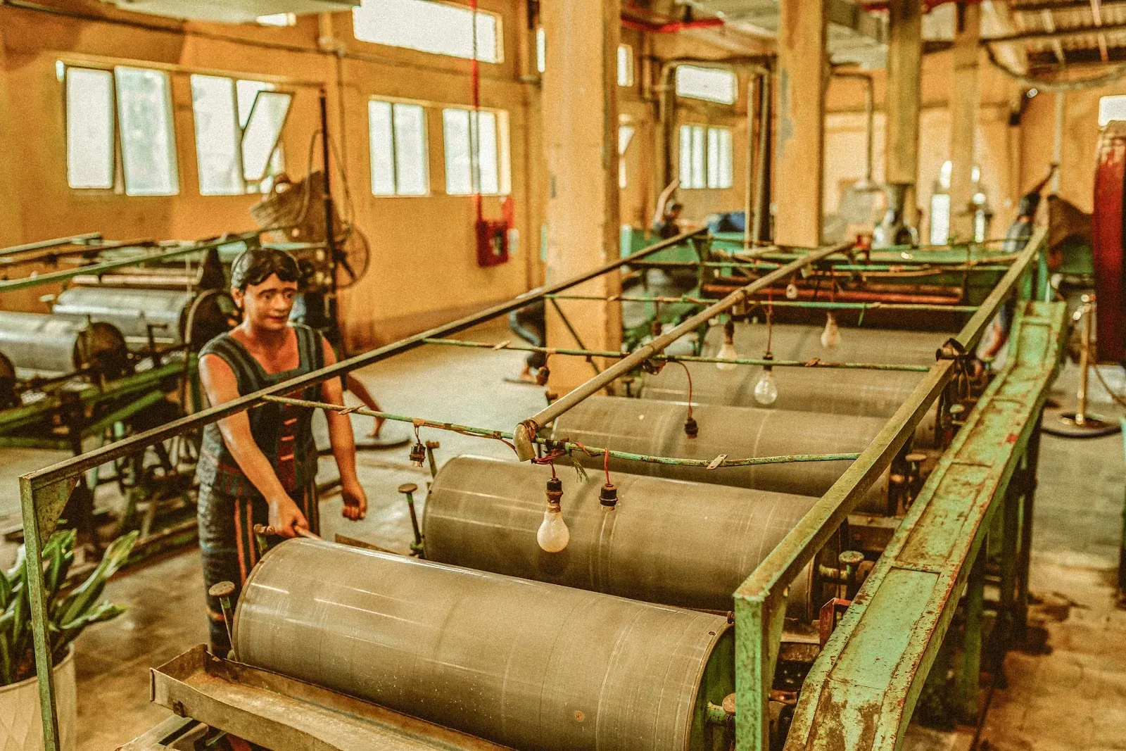 Dãy máy tách sơ râu với các trục tròn và tượng người thợ vận hành